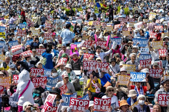 People hold placards reading “No war” and “Stop constitutional revision, military expansion” during the Grand Constitution Rally 2026 to mark Constitution Memorial Day in Tokyo on May 3, 2026. (Photo by Philip FONG / AFP)