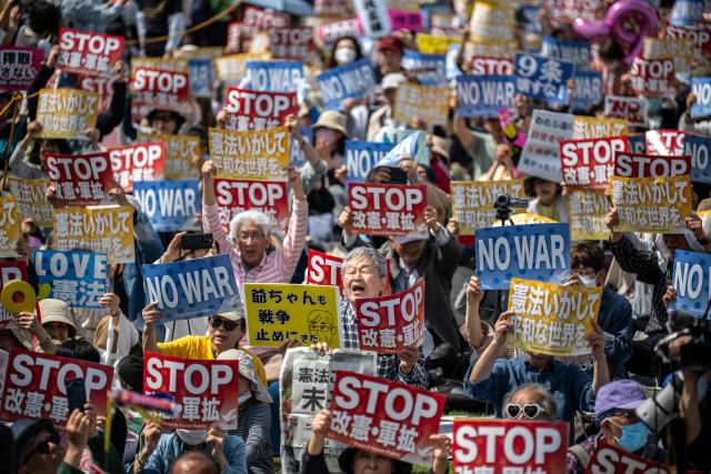 People hold placards reading “No war” and “Stop constitutional revision, military expansion” during the Grand Constitution Rally 2026 to mark Constitution Memorial Day in Tokyo on May 3, 2026. (Photo by Philip FONG / AFP)