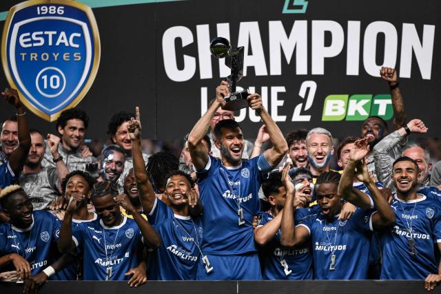 Troyes' players and staff celebrate with the French Ligue 2 championship trophy after winning the French L2 football match between Troyes and Laval at the stade de l'Aube in Troyes, eastern France, on May 2, 2026. (Photo by ARNAUD FINISTRE / AFP)