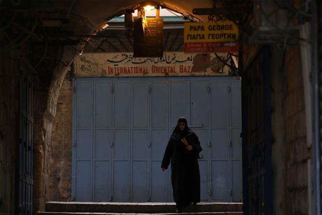 A nun carrying candles, walks towards the Church of the Holy Sepulchre in the old city of Jerusalem on May 3, 2026. (Photo by HAZEM BADER / AFP)