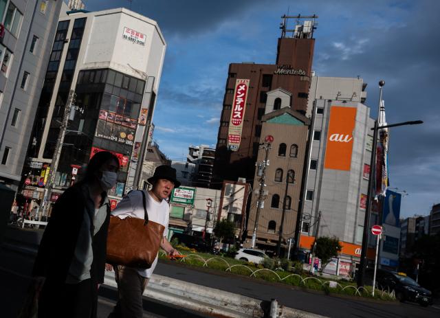 Two people walk through a shopping district on the way to the metro station in Tokyo on May 3, 2026. (Photo by ANDREW CABALLERO-REYNOLDS / AFP)