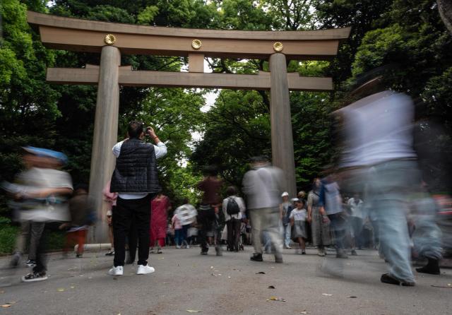 A tourist takes a photo as others enter the grounds of the Meiji Jingu Shinto shrine in Tokyo on May 3, 2026. (Photo by ANDREW CABALLERO-REYNOLDS / AFP)