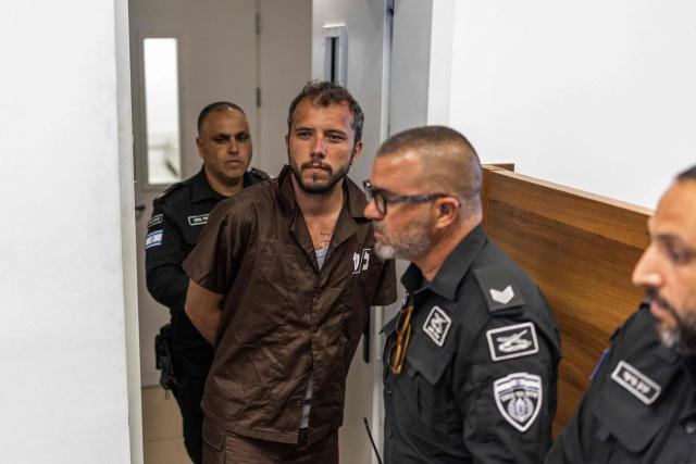 Security personnel escort Brazilian activist Thiago Avila to a court in Ashkelon on May 3, 2026. Two foreign activists from a Gaza-bound flotilla who were brought to Israel for interrogation appeared before an Israeli court on May 3, a rights group defending them told AFP. The flotilla of more than 50 vessels had set sail from France, Spain and Italy with the aim of breaking an Israeli blockade of Gaza and bringing supplies to the devastated Palestinian territory. (Photo by Ilia YEFIMOVICH / AFP)