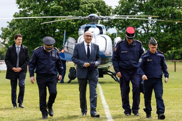 France's Interior Minister Laurent Nunez (C) arrives after flying over the site of a "teknival" rave party at a military site in Cornusse, near Bourges, central France on May 3, 2026. Between 17,000 and 40,000 people participate in the free party which has been taking place, without major incident, since May 1, 2026. The gathering comes as the French parliament is seeking to tighten legislation against unauthorised rave parties, introducing prison sentences for organisers and fines for attendees. (Photo by Kenzo TRIBOUILLARD / AFP)