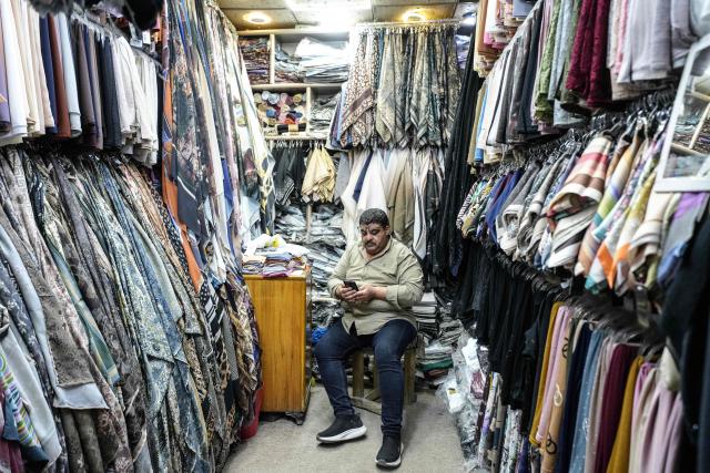 (FILES) A shop owner waits for custormers in the Old City of Najaf on April 22, 2026. In Iraq's holy city of Najaf, the majestic shrine of Imam Ali stands quieter than usual, its vast courtyards no longer filled with pilgrims whose whispers once echoed, melding in different languages. In nearby markets, shopkeepers and hotel owners have little to do. Their days drag on as they hope for tourists to come through their doors and revive their businesses. (Photo by Qassem al-KAABI / AFP)