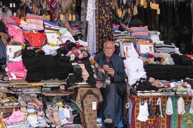 (FILES) A shop owner waits for custormers in the Old City of Najaf on April 22, 2026. In Iraq's holy city of Najaf, the majestic shrine of Imam Ali stands quieter than usual, its vast courtyards no longer filled with pilgrims whose whispers once echoed, melding in different languages. In nearby markets, shopkeepers and hotel owners have little to do. Their days drag on as they hope for tourists to come through their doors and revive their businesses. (Photo by Qassem al-KAABI / AFP)