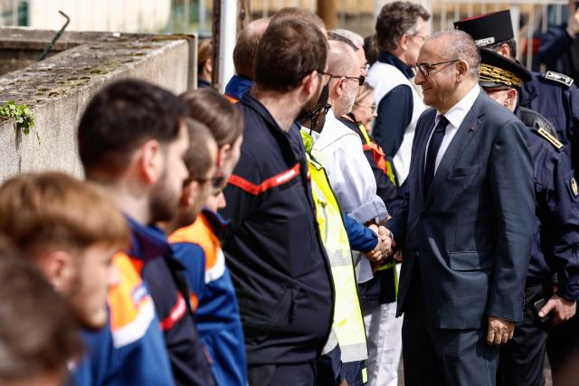 France's Interior Minister Laurent Nunez (R) greets firefighters, emergency medical service and civil protection members as he visits an advanced medical post on the sidelines of a "teknival" rave party at a military site in Cornusse, near Bourges, in Bengy-sur-Craon, central France on May 3, 2026. Between 17,000 and 40,000 people participate in the free party which has been taking place, without major incident, since May 1, 2026. The gathering comes as the French parliament is seeking to tighten legislation against unauthorised rave parties, introducing prison sentences for organisers and fines for attendees. (Photo by Kenzo TRIBOUILLARD / POOL / AFP)