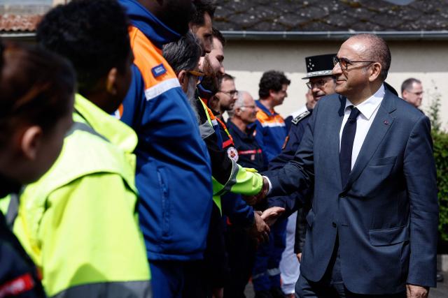 France's Interior Minister Laurent Nunez (R) greets firefighters, emergency medical service and civil protection members as he visits an advanced medical post on the sidelines of a "teknival" rave party at a military site in Cornusse, near Bourges, in Bengy-sur-Craon, central France on May 3, 2026. Between 17,000 and 40,000 people participate in the free party which has been taking place, without major incident, since May 1, 2026. The gathering comes as the French parliament is seeking to tighten legislation against unauthorised rave parties, introducing prison sentences for organisers and fines for attendees. (Photo by Kenzo TRIBOUILLARD / POOL / AFP)
