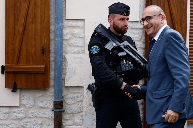 France's Interior Minister Laurent Nunez (R) greets a French gendarme as he arrives near a "teknival" rave party at a military site in Cornusse, near Bourges, in Bengy-sur-Craon, central France on May 3, 2026. Between 17,000 and 40,000 people participate in the free party which has been taking place, without major incident, since May 1, 2026. The gathering comes as the French parliament is seeking to tighten legislation against unauthorised rave parties, introducing prison sentences for organisers and fines for attendees. (Photo by Kenzo TRIBOUILLARD / POOL / AFP)