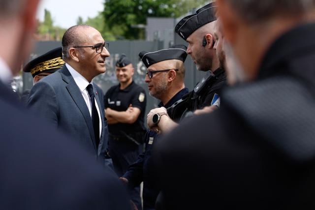 France's Interior Minister Laurent Nunez greets a French gendarmes near the gendarmerie near a "teknival" rave party at a military site in Baugy, near Bourges, central France on May 3, 2026. Between 17,000 and 40,000 people participate in the free party which has been taking place, without major incident, since May 1, 2026. The gathering comes as the French parliament is seeking to tighten legislation against unauthorised rave parties, introducing prison sentences for organisers and fines for attendees. (Photo by Kenzo TRIBOUILLARD / AFP)