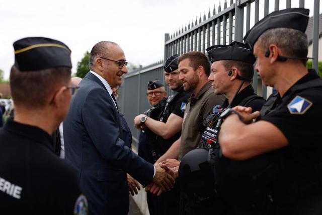 France's Interior Minister Laurent Nunez greets a French gendarmes near the gendarmerie near a "teknival" rave party at a military site in Baugy, near Bourges, central France on May 3, 2026. Between 17,000 and 40,000 people participate in the free party which has been taking place, without major incident, since May 1, 2026. The gathering comes as the French parliament is seeking to tighten legislation against unauthorised rave parties, introducing prison sentences for organisers and fines for attendees. (Photo by Kenzo TRIBOUILLARD / AFP)