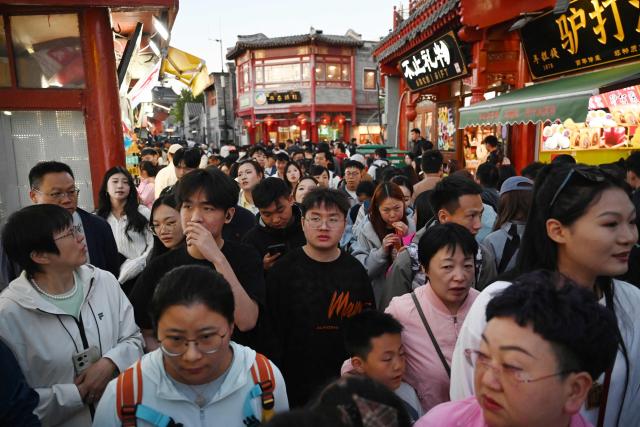 People crowd an alley at a tourist area in Beijing on May 3, 2026, the third day of a five-day national May Day holiday. (Photo by GREG BAKER / AFP)