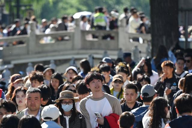 People crowd an alley beside Houhai Lake in Beijing on May 3, 2026, the third day of a five-day national May Day holiday. (Photo by GREG BAKER / AFP)