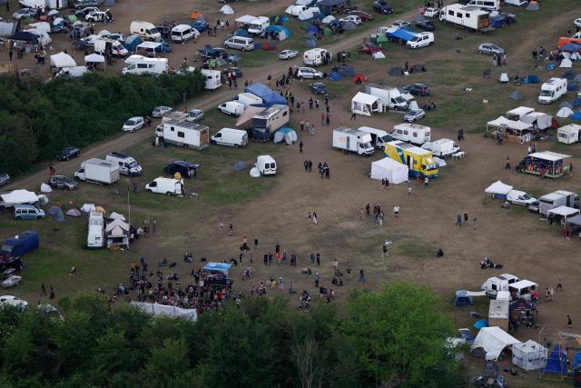 An aerial view shows partygoers gathering at a sound system at the of a "teknival" rave party at a military site in Cornusse, near Bourges, central France on May 3, 2026. Between 17,000 and 40,000 people participate in the free party which has been taking place, without major incident, since May 1, 2026. The gathering comes as the French parliament is seeking to tighten legislation against unauthorised rave parties, introducing prison sentences for organisers and fines for attendees. (Photo by Kenzo TRIBOUILLARD / AFP)
