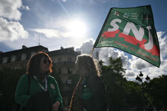 A woman holds a National Union of Journalists (SNJ) union flag during a gathering outside Paris' city hall to mark World Press Freedom Day in Paris on May 3, 2026. (Photo by Julie SEBADELHA / AFP)