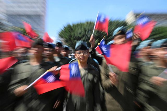 Guatemalan cadets hold Taiwanese flags as navy cadets from a friendship squadron from Taiwan perform in a music band at Constitution Square in Guatemala City on May 3, 2026. The three vessels -- described as being on a training mission -- powered into Puerto Quetzal, a port town on Guatemala's Pacific coast, in a visit "to strengthen the ties of friendship," Guatemalan officials and Taiwanese diplomats said. (Photo by JOHAN ORDONEZ / AFP)
