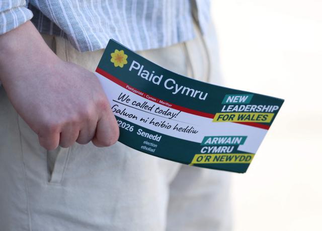 A Plaid Cymru canvasser holds a flyer whilst knocking doors with candidate Heledd Fychan ahead of the Senedd election in Pontypridd, South Wales on April 24, 2026. Wales -- the cradle of Britain's revered National Health Service and a former industrial powerhouse -- has been a Labour Party stronghold for well over a century. But that is set to end in crunch polls next week as impatient Britons abandon their old political loyalties for anti-establishment parties amid persistent cost of living pressures. (Photo by Darren Staples / AFP) / TO GO WITH AFP STORY by Peter HUTCHISON