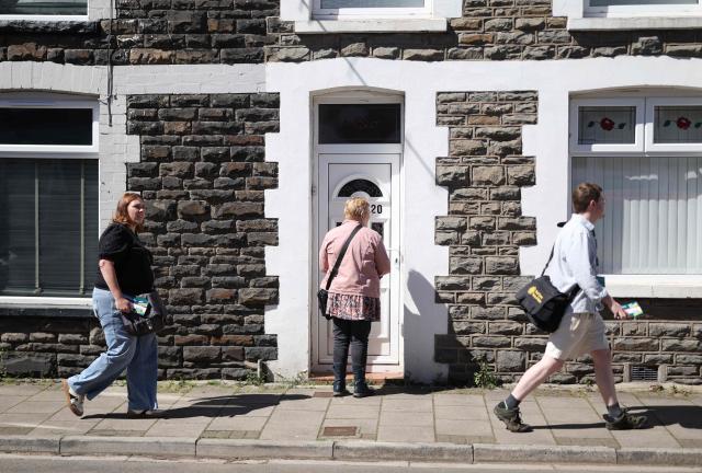 Plaid Cymru canvassers knock doors with candidate Heledd Fychan (L) ahead of the Senedd election in Pontypridd, South Wales on April 24, 2026. Wales -- the cradle of Britain's revered National Health Service and a former industrial powerhouse -- has been a Labour Party stronghold for well over a century. But that is set to end in crunch polls next week as impatient Britons abandon their old political loyalties for anti-establishment parties amid persistent cost of living pressures. (Photo by Darren Staples / AFP) / TO GO WITH AFP STORY by Peter HUTCHISON