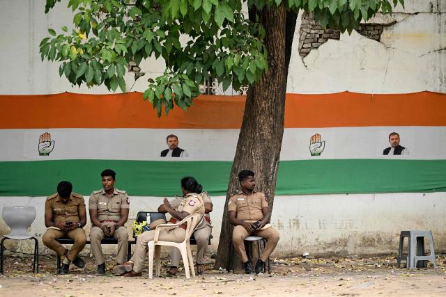 Police personnel take shade next to a banner featuring Indian National Congress (INC) party leader Rahul Gandhi, during vote counting for the Tamil Nadu Legislative Assembly elections at the Tamil Nadu Congress Committee office in Chennai on May 4, 2026. (Photo by R. Satish BABU / AFP)