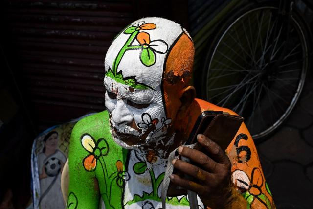 A supporter with the All India Trinamool Congress (TMC) party election symbol painted on his body uses his mobile phone along a street near the residence of West Bengal chief minister and party chairperson Mamata Banerjee in Kolkata on May 4, 2026 during vote counting for the West Bengal Legislative Assembly elections. Vote counting in key Indian state elections was underway on May 4 under tight security, with the focus on West Bengal, where Prime Minister Narendra Modi's party appeared set for victory. (Photo by Dibyangshu SARKAR / AFP)