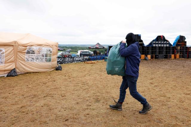 A partygoer cleans the military site where a "teknival" rave party took place in Cornusse, near Bourges, central France on May 4, 2026. Between 17,000 and 40,000 people participate in the free party which has been taking place, without major incident, since May 1, 2026. The gathering comes as the French parliament is seeking to tighten legislation against unauthorised rave parties, introducing prison sentences for organisers and fines for attendees. (Photo by Kenzo TRIBOUILLARD / AFP)