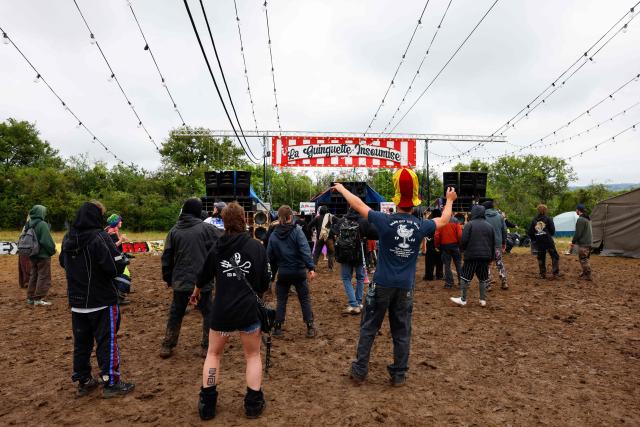 Partygoers stand in front of a stage at the end of a "teknival" rave party at a military site in Cornusse, near Bourges, central France on May 4, 2026. Between 17,000 and 40,000 people participate in the free party which has been taking place, without major incident, since May 1, 2026. The gathering comes as the French parliament is seeking to tighten legislation against unauthorised rave parties, introducing prison sentences for organisers and fines for attendees. (Photo by Kenzo TRIBOUILLARD / AFP)