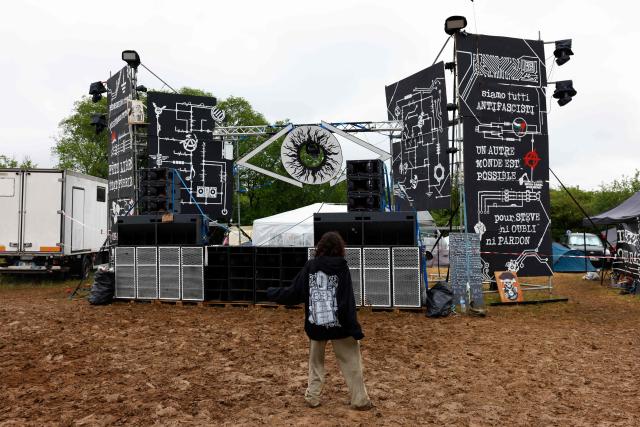 A partygoer stands in front of a stage at the end of a "teknival" rave party at a military site in Cornusse, near Bourges, central France on May 4, 2026. Between 17,000 and 40,000 people participate in the free party which has been taking place, without major incident, since May 1, 2026. The gathering comes as the French parliament is seeking to tighten legislation against unauthorised rave parties, introducing prison sentences for organisers and fines for attendees. (Photo by Kenzo TRIBOUILLARD / AFP)