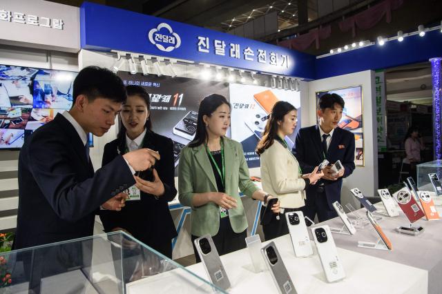 Visitors browse domestically produced Jindallae mobile phones during the 24th Pyongyang Spring International Trade Fair opening at the Central Youth Hall in Pyongyang on May 4, 2026. (Photo by KIM Won Jin / AFP)