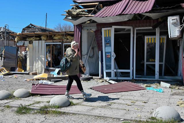A woman walks past damaged stores at the site of a Russian missile strike in the town of Merefa, Kharkiv region, on May 4, 2026, amid the Russian invasion of Ukraine. The strike hit the town of Merefa, which has faced heavy attacks by Russia in the more than four years of its invasion. (Photo by SERGEY BOBOK / AFP)