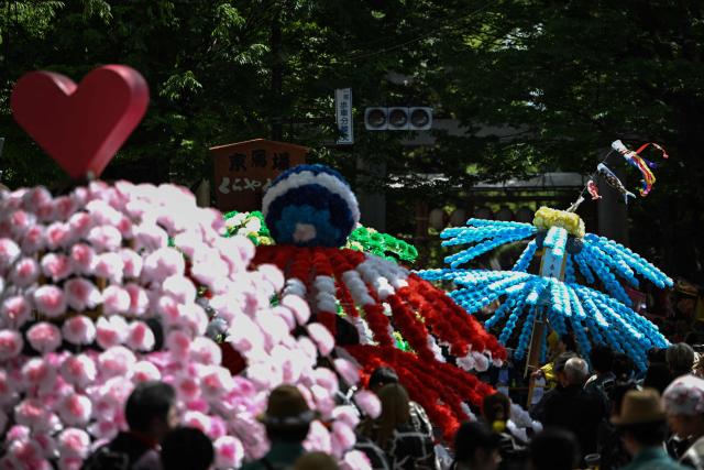 A festival participant spins an elaborate three-meter-tall decorated lantern tower known as Mant? through the streets of Fuchu during the Kurayami Matsuri, or "Festival of Darkness," at Okunitama Shrine in western Tokyo on May 4, 2026, as neighbourhood groups compete in an ancient tradition to keep their 50-kilogram towers twirling the longest while judges assess the artistry of each team's decorated pole. (Photo by Andrew CABALLERO-REYNOLDS / AFP)