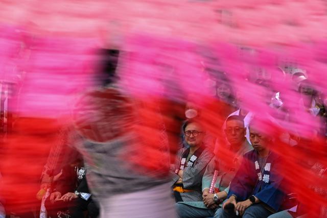 Judges watch as a festival participant spins an elaborate three-meter-tall decorated lantern tower known as Mant? through the streets of Fuchu during the Kurayami Matsuri, or "Festival of Darkness," at Okunitama Shrine in western Tokyo on May 4, 2026, as neighbourhood groups compete in an ancient tradition to keep their 50-kilogram towers twirling the longest while judges assess the artistry of each team's decorated pole. (Photo by Andrew CABALLERO-REYNOLDS / AFP)