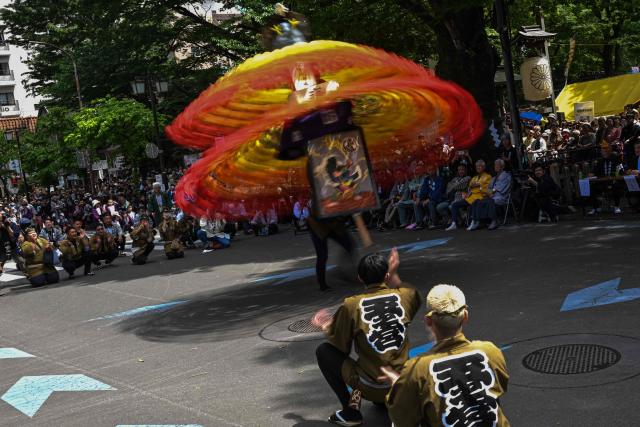 A festival participant spins an elaborate three-meter-tall decorated lantern tower known as Mant? through the streets of Fuchu during the Kurayami Matsuri, or "Festival of Darkness," at Okunitama Shrine in western Tokyo on May 4, 2026, as neighbourhood groups compete in an ancient tradition to keep their 50-kilogram towers twirling the longest while judges assess the artistry of each team's decorated pole. (Photo by Andrew CABALLERO-REYNOLDS / AFP)