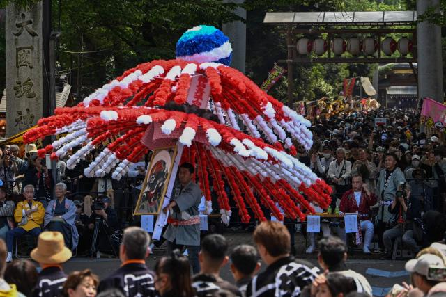A festival participant spins an elaborate three-meter-tall decorated lantern tower known as Mant? through the streets of Fuchu during the Kurayami Matsuri, or "Festival of Darkness," at Okunitama Shrine in western Tokyo on May 4, 2026, as neighbourhood groups compete in an ancient tradition to keep their 50-kilogram towers twirling the longest while judges assess the artistry of each team's decorated pole. (Photo by Andrew CABALLERO-REYNOLDS / AFP)