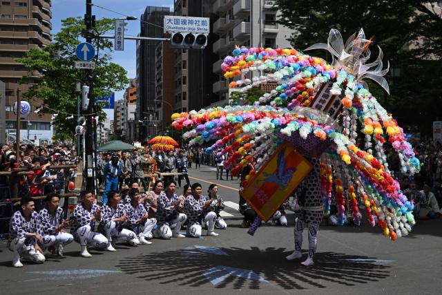 A festival participant spins an elaborate three-meter-tall decorated lantern tower known as Mant? through the streets of Fuchu during the Kurayami Matsuri, or "Festival of Darkness," at Okunitama Shrine in western Tokyo on May 4, 2026, as neighbourhood groups compete in an ancient tradition to keep their 50-kilogram towers twirling the longest while judges assess the artistry of each team's decorated pole. (Photo by Andrew CABALLERO-REYNOLDS / AFP)