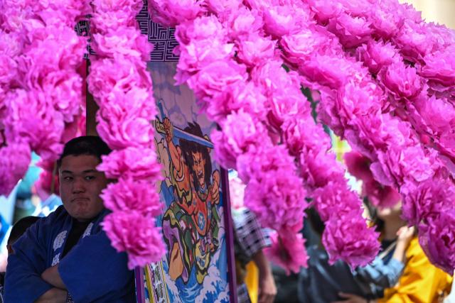 A festival participant rest before spinning an elaborate three-meter-tall decorated lantern tower known as Mant? through the streets of Fuchu during the Kurayami Matsuri, or "Festival of Darkness," at Okunitama Shrine in western Tokyo on May 4, 2026, as neighbourhood groups compete in an ancient tradition to keep their 50-kilogram towers twirling the longest while judges assess the artistry of each team's decorated pole. (Photo by Andrew CABALLERO-REYNOLDS / AFP)