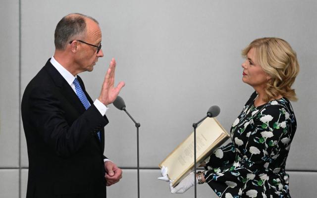 (FILES) Designated German Chancellor Friedrich Merz takes the oath of office from President of the Bundestag (lower house of parliament) Julia Kloeckner during a swearing-in ceremony at the Bundestag (lower house of parliament) in Berlin on May 6, 2025. German lawmakers on May 6, 2025 elected conservative Friedrich Merz as chancellor in a second-round vote, a victory marred by his surprise defeat in an initial ballot. A year after German Chancellor Friedrich Merz took office vowing to revive the political centre, the far-right AfD party has risen to the top of the polls while Merz's coalition faces miserable approval numbers. (Photo by Tobias SCHWARZ / AFP)