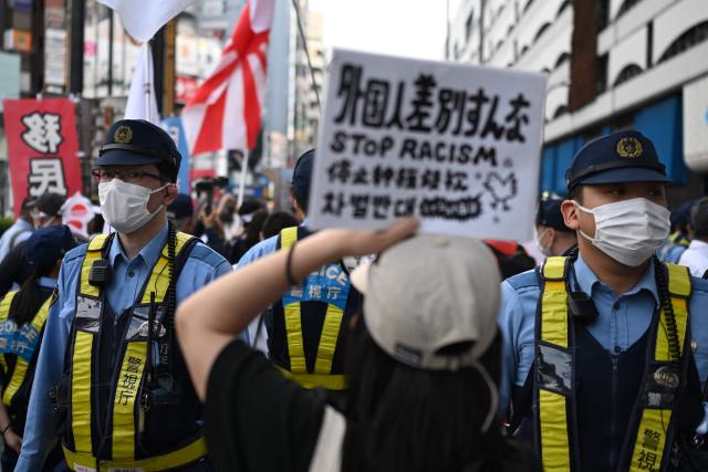 A counter protester holds up a sign during a nationalist rally near Ikebukuro Station in Tokyo's Toshima district on May 4, 2026, where participants called for stricter immigration controls and denounced the Japan Communist Party. (Photo by Andrew CABALLERO-REYNOLDS / AFP)