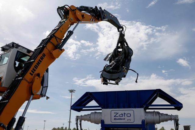 A Liebherr LH30 material handler (L) moves an old car into a Zato recycling shredder machine at the IFAT Munich, the world's leading trade fair dedicated to environmental technologies across water, wastewater, waste and resource management, in Munich, Bavaria, southern Germany, on May 4, 2026. At the fair, which runs until May 7, 2026, over 3,000 exhibitors from more than 60 countries will present their strategies and innovations, according to organisers. (Photo by Michaela STACHE / AFP)