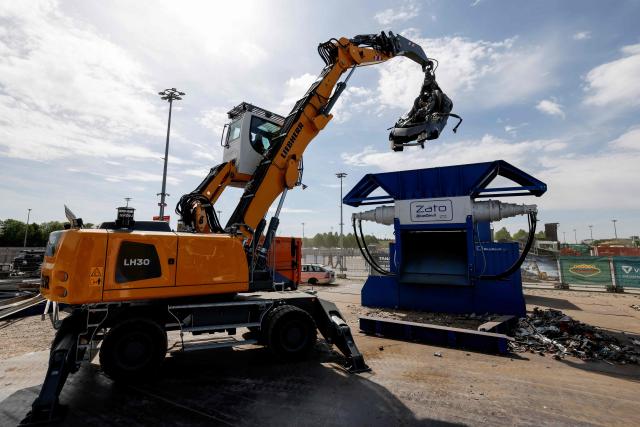 A Liebherr LH30 material handler (L) moves an old car into a Zato recycling shredder machine at the IFAT Munich, the world's leading trade fair dedicated to environmental technologies across water, wastewater, waste and resource management, in Munich, Bavaria, southern Germany, on May 4, 2026. At the fair, which runs until May 7, 2026, over 3,000 exhibitors from more than 60 countries will present their strategies and innovations, according to organisers. (Photo by Michaela STACHE / AFP)