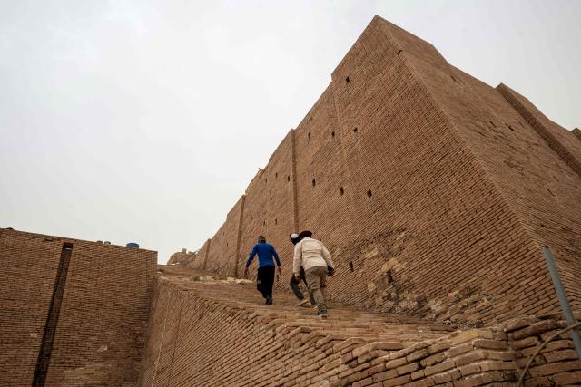 Members of the Iraqi Antiquities Authority maintenance team, walks up the stairs as ongoing work takes place to restore the Great Ziggurat temple in the ancient city of Ur, believed to be the birthplace of Abraham, the patriarch of the worlds three monotheistic religions, located now in  Iraq's southern Dhi Qar province, some 16 kilometres from the centre of the city of Nasiriyah, on May 4, 2026. The ziggurat, one of several structures built by the ancient Sumerians in what is now modern-day Iraq, was believed to be the dwelling place of the gods. The temple at its summit was therefore off-limits to all but priests and other highly revered figures. Today, the Great Ziggurat is undergoing careful restoration, carried out by local craftsmen using regionally sourced materials, including bricks specially produced to match original ancient samples. (Photo by Assad NIYAZI / AFP)