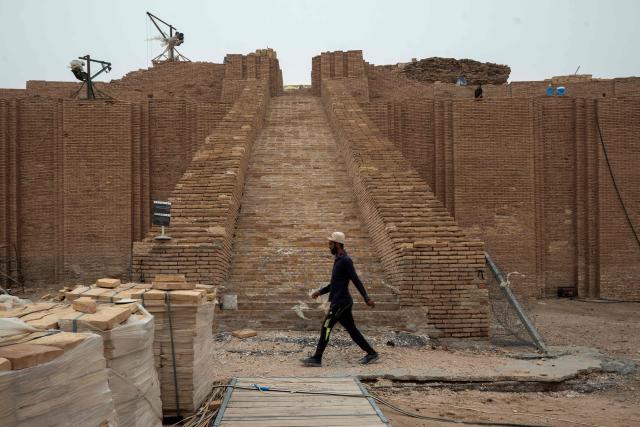 A member of the Iraqi Antiquities Authority maintenance team, walks along a path as works take place to restore the Great Ziggurat temple in the ancient city of Ur, believed to be the birthplace of Abraham, the patriarch of the worlds three monotheistic religions, located now in  Iraq's southern Dhi Qar province, some 16 kilometres from the centre of the city of Nasiriyah, on May 4, 2026. The ziggurat, one of several structures built by the ancient Sumerians in what is now modern-day Iraq, was believed to be the dwelling place of the gods. The temple at its summit was therefore off-limits to all but priests and other highly revered figures. Today, the Great Ziggurat is undergoing careful restoration, carried out by local craftsmen using regionally sourced materials, including bricks specially produced to match original ancient samples. (Photo by Assad NIYAZI / AFP)