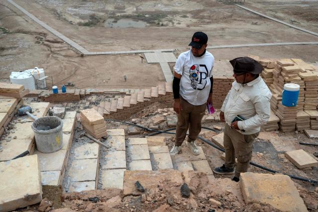 Members the Iraqi Antiquities Authority maintenance team discus the restoration work of the Great Ziggurat temple in the ancient city of Ur, believed to be the birthplace of Abraham, the patriarch of the worlds three monotheistic religions, located now in  Iraq's southern Dhi Qar province, some 16 kilometres from the centre of the city of Nasiriyah, on May 4, 2026. The ziggurat, one of several structures built by the ancient Sumerians in what is now modern-day Iraq, was believed to be the dwelling place of the gods. The temple at its summit was therefore off-limits to all but priests and other highly revered figures. Today, the Great Ziggurat is undergoing careful restoration, carried out by local craftsmen using regionally sourced materials, including bricks specially produced to match original ancient samples. (Photo by Assad NIYAZI / AFP)