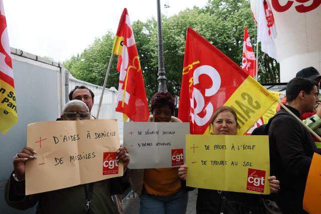 Demonstrators hold placards reading "Public money for public school, not for war" during a rally in front of the National Assembly to protest against the military spending bill, in Paris on May 4, 2026. (Photo by Xavier GALIANA / AFP)