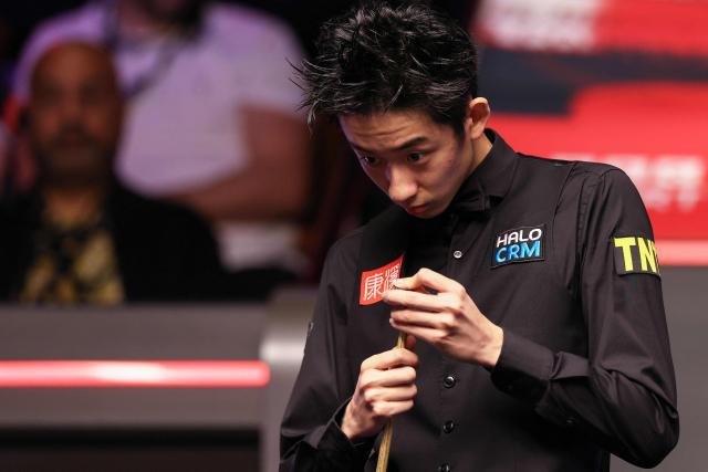 China's Wu Yize eyes the table as he plays against England's Shaun Murphy during the World Snooker Championship final round at The Crucible in Sheffield, northern England on May 4, 2026. (Photo by Darren Staples / AFP)