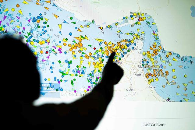A photo illustration taken in Nicosia on May 4, 2026, shows a person in front of a large screen displaying vessel movements in the Strait of Hormuz on a ship-tracking website. Iran's navy fired 'warning shots' at US warships in the Strait of Hormuz on May 4, state media said, after the American military sent cruisers into the Gulf as part of a plan to help trapped commercial vessels leave. Earlier, US President Donald Trump had announced a plan to guide ships from neutral countries out of the Gulf, saying it was a humanitarian effort to help their stranded crews. (Photo by AFP)