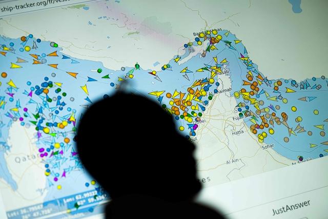 A photo illustration taken in Nicosia on May 4, 2026, shows a person in front of a large screen displaying vessel movements in the Strait of Hormuz on a ship-tracking website. Iran's navy fired 'warning shots' at US warships in the Strait of Hormuz on May 4, state media said, after the American military sent cruisers into the Gulf as part of a plan to help trapped commercial vessels leave. Earlier, US President Donald Trump had announced a plan to guide ships from neutral countries out of the Gulf, saying it was a humanitarian effort to help their stranded crews. (Photo by AFP)