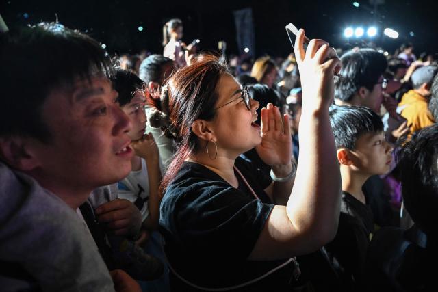 People sing along during a free music concert in a park in Beijing on May 4, 2026, the fourth day of a five-day national May Day holiday. (Photo by GREG BAKER / AFP)