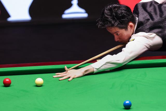 China's Wu Yize plays a shot against England's Shaun Murphy during the World Snooker Championship final round at The Crucible in Sheffield, northern England on May 4, 2026. (Photo by Darren Staples / AFP)
