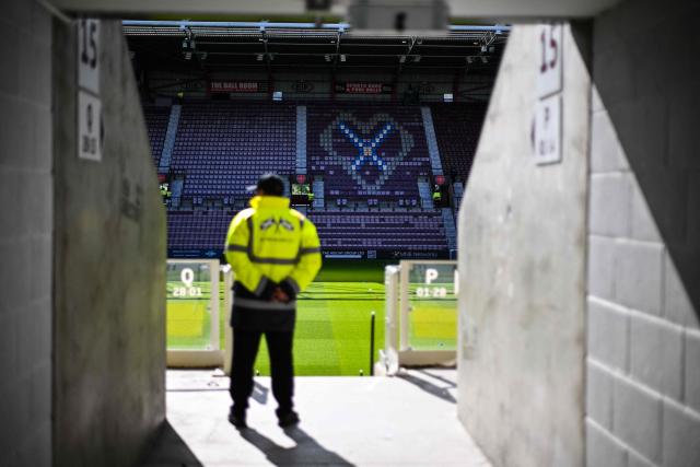 A member of security monitors the area before the start of the Scottish Premiership football match between Hearts and Rangers at Tynecastle Stadium in Edinburgh on May 4, 2026. Hearts are hoping to become the first club other than Celtic and Rangers to win the Scottish crown since Aberdeen in 1985. (Photo by ANDY BUCHANAN / AFP)