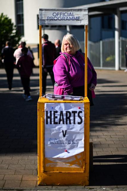A programme vendor waits for customers before the start of the Scottish Premiership football match between Hearts and Rangers outside Tynecastle Stadium in Edinburgh on May 4, 2026. Hearts are hoping to become the first club other than Celtic and Rangers to win the Scottish crown since Aberdeen in 1985. (Photo by ANDY BUCHANAN / AFP)
